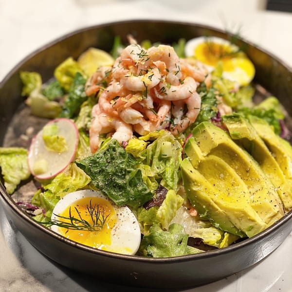 Shrimp salad with avocado, soft-boiled eggs, radish, and dill in a dark bowl at Waxin's.