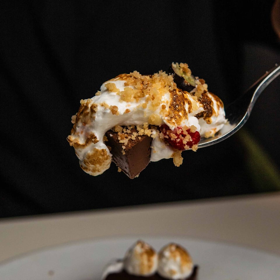 A spoonful of Waxin's chocolate dessert with toasted meringue, raspberries, and cookie crumble.