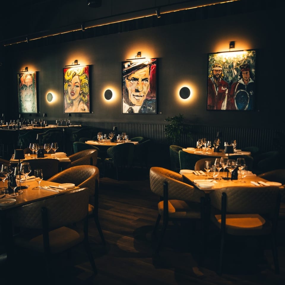 Dimly lit Waxin's dining room with modern art, set tables, and plush chairs.
